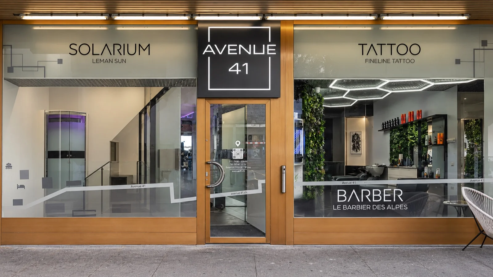 Mise en situation : vitrine et entrée d’Avenue 41 entre un solarium, un salon de tatouage et un barbier
