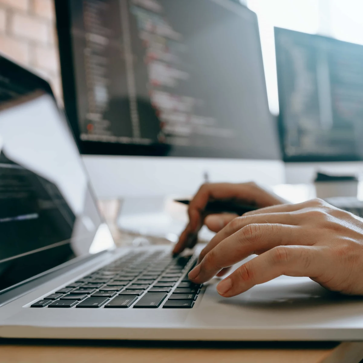 Mains tapant sur un ordinateur portable ouvert sur du code