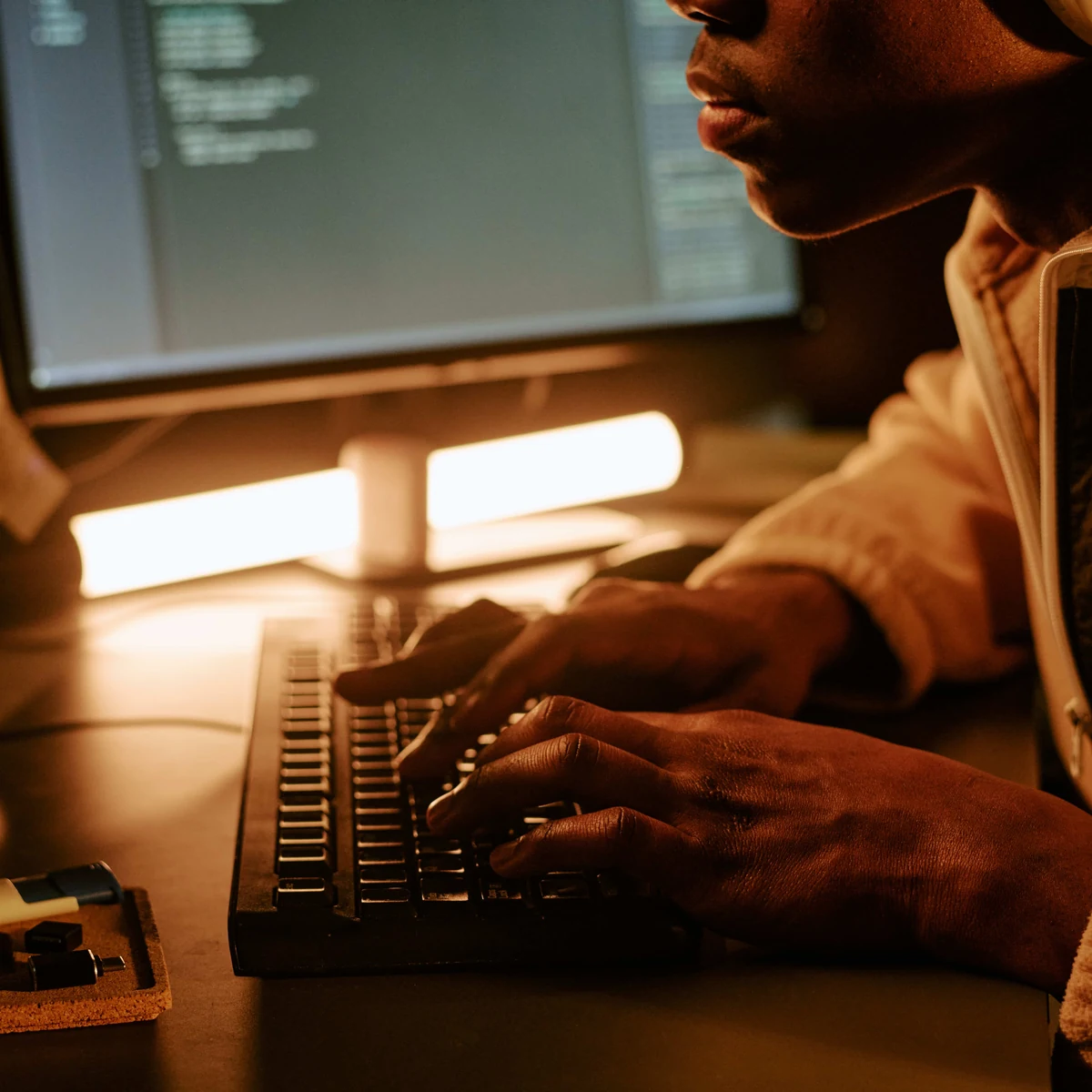 Développeur tapant sur un clavier mécanique, éclairage chaleureux