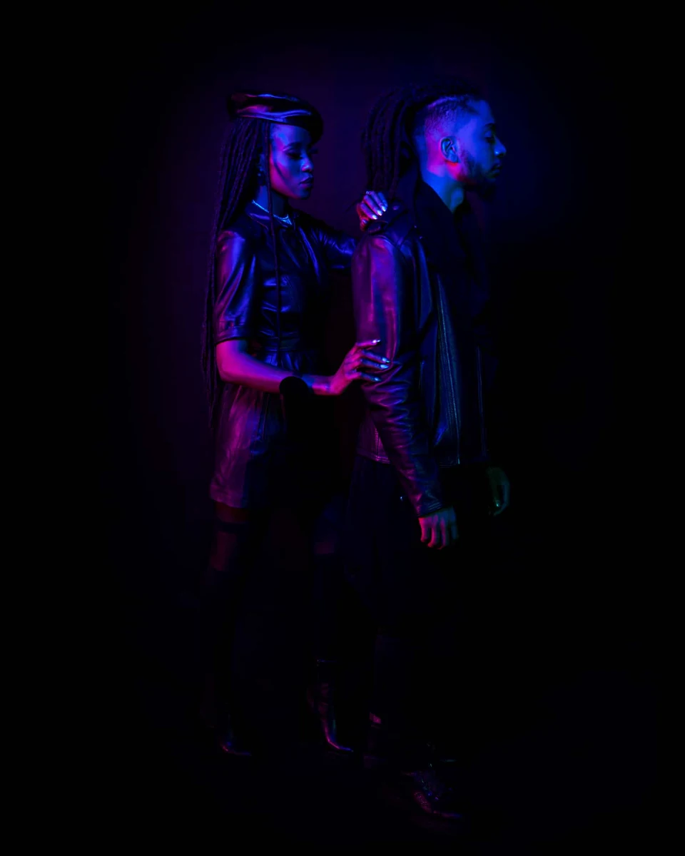 Portrait de deux modèles dans une ambiance néon violette sur fond noir