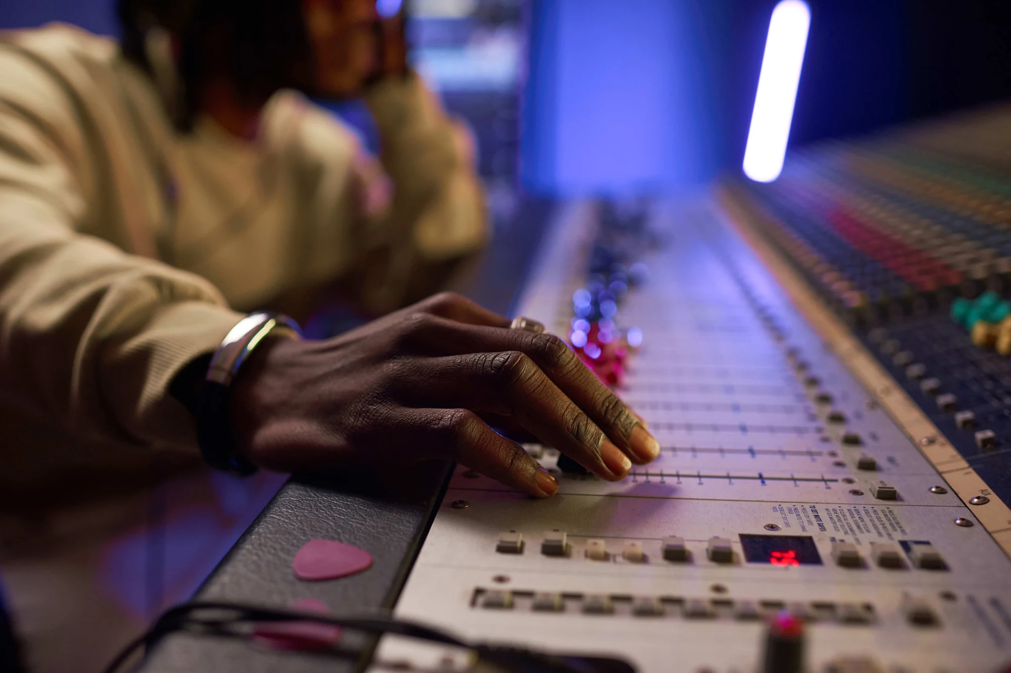 Ingénieur du son les mains sur la console de mixage, lumières néon