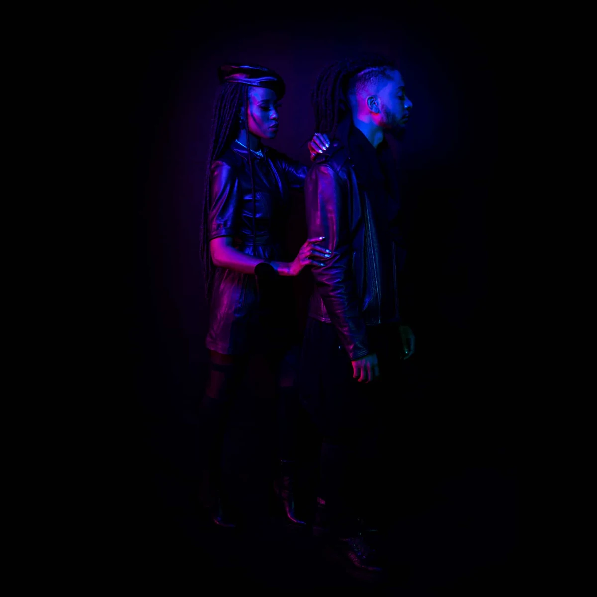Deux artistes en lumière néon pourpre et bleue sur fond noir