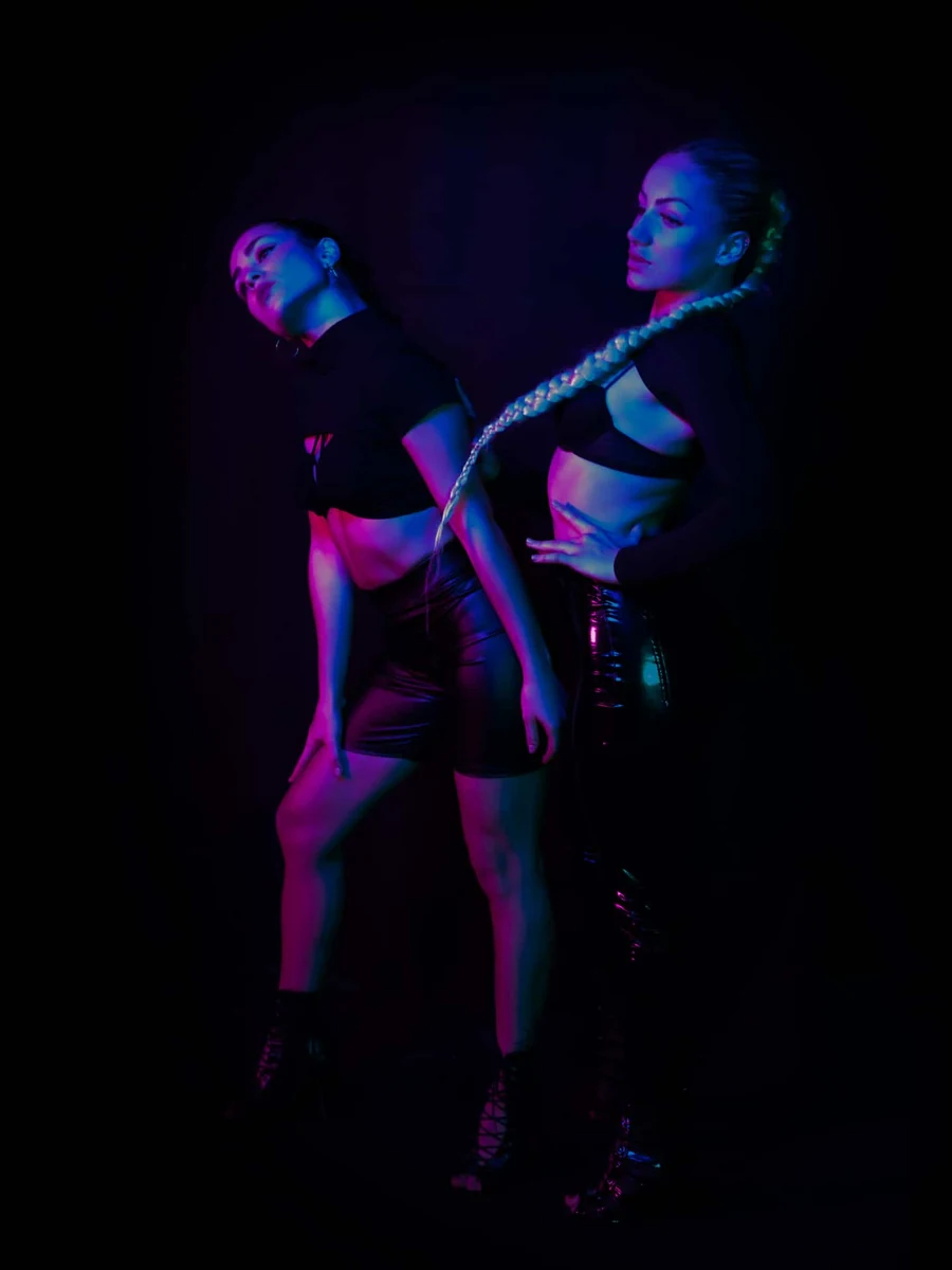 Deux artistes en lumière néon rose et bleue sur fond noir
